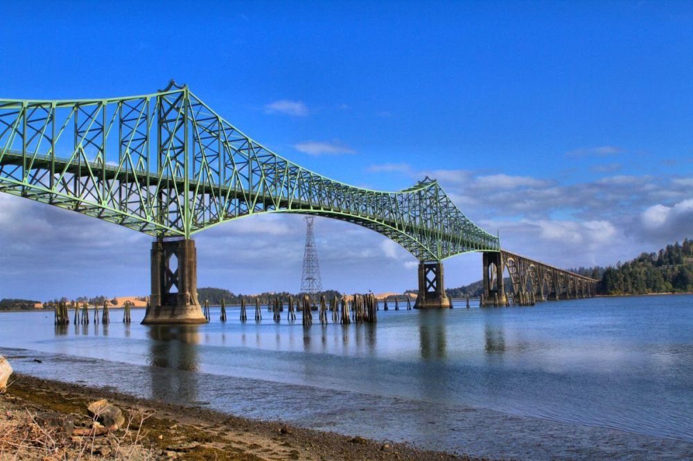 The Conde B. McCullough Memorial Bridge crosses Coos Bay on U.S. Route 101 near North Bend. The green girders rise above blue water.